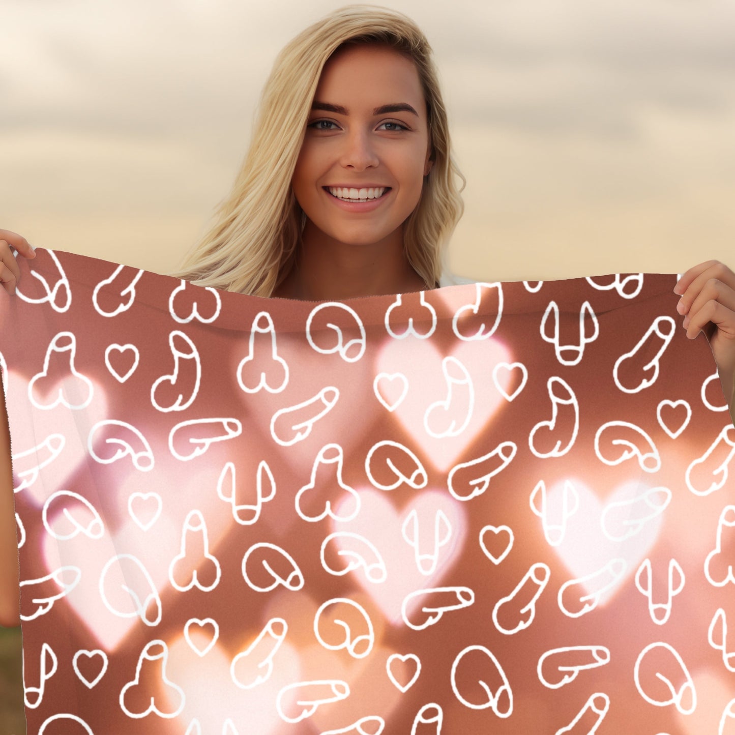 Woman holding a pinkish blanket with white heart and penis patterns against a blurred natural background