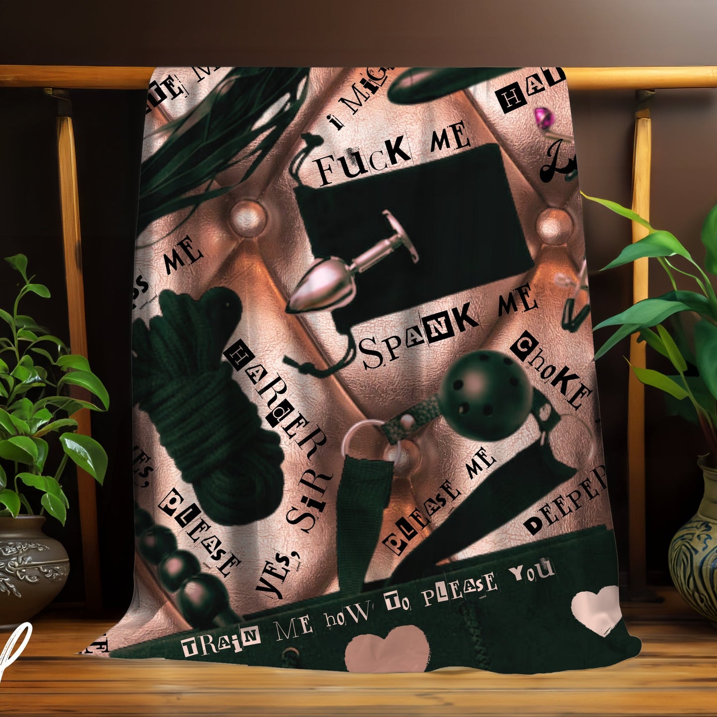 Decorative blanket with graphic BDSM themed designs and text on a wooden stand with plants.