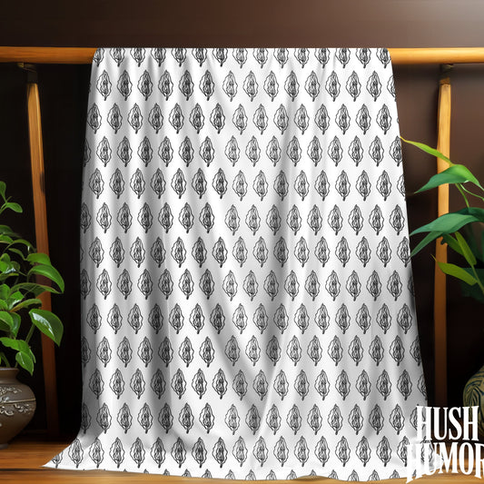 White fabric with black vagina print pattern draped over a wooden rack with plants on either side.