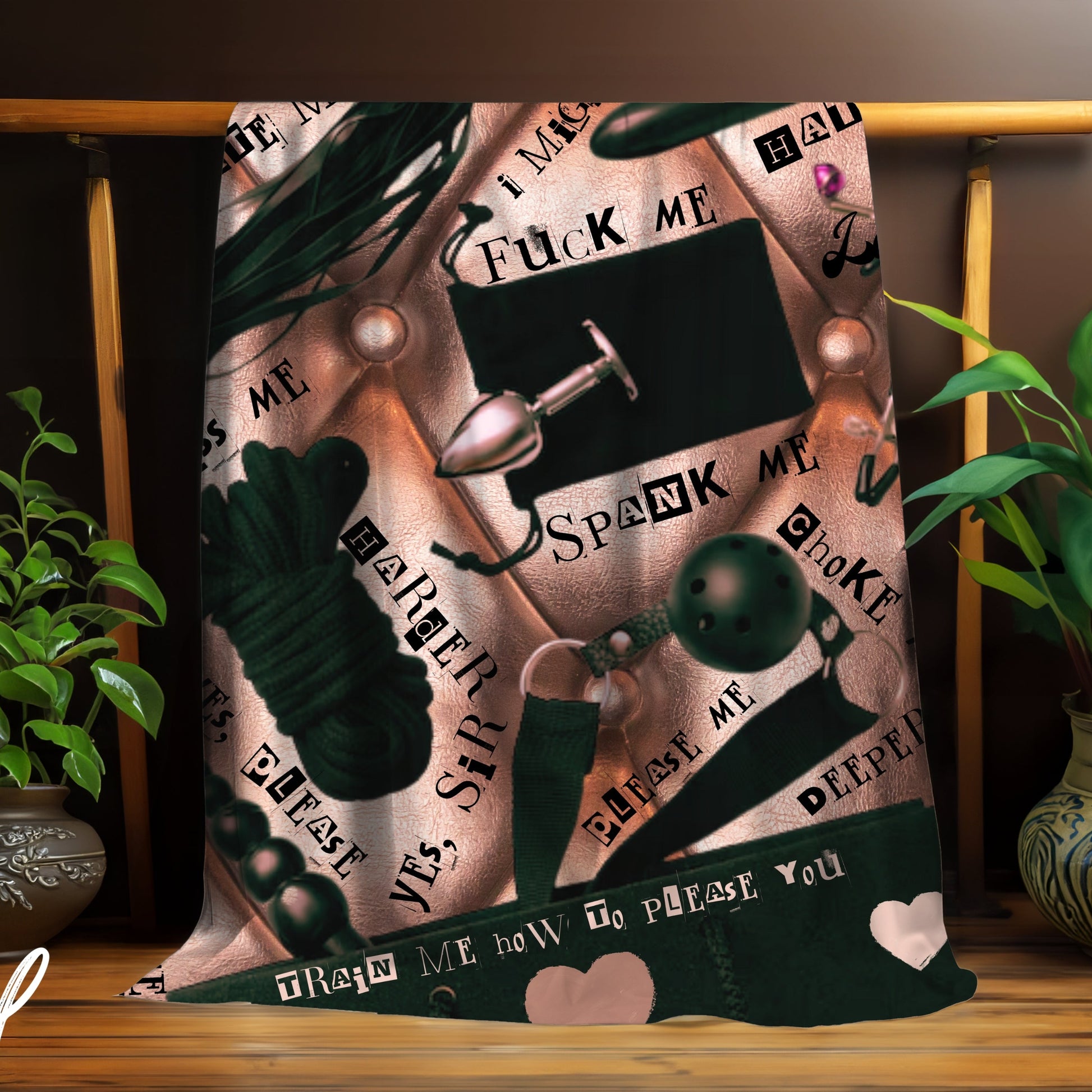 Decorative blanket with graphic BDSM themed designs and text on a wooden stand with plants.